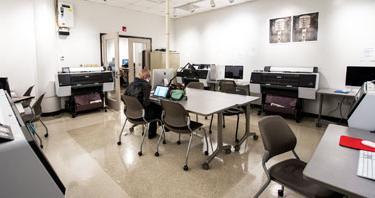 A wide view of the Photography Studio showing desks, computer workstations and large format printers.