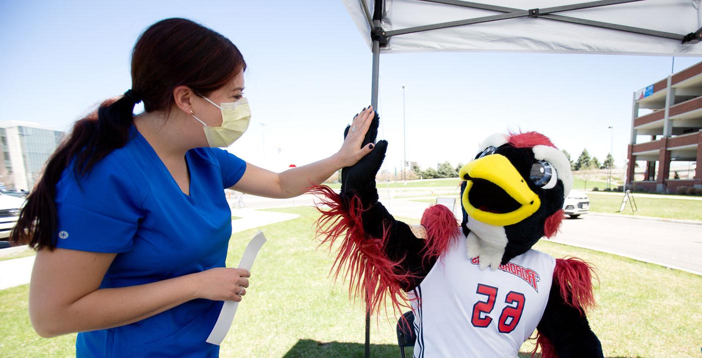 Rowdy Mascot high fiving a healthcare student in scrubs