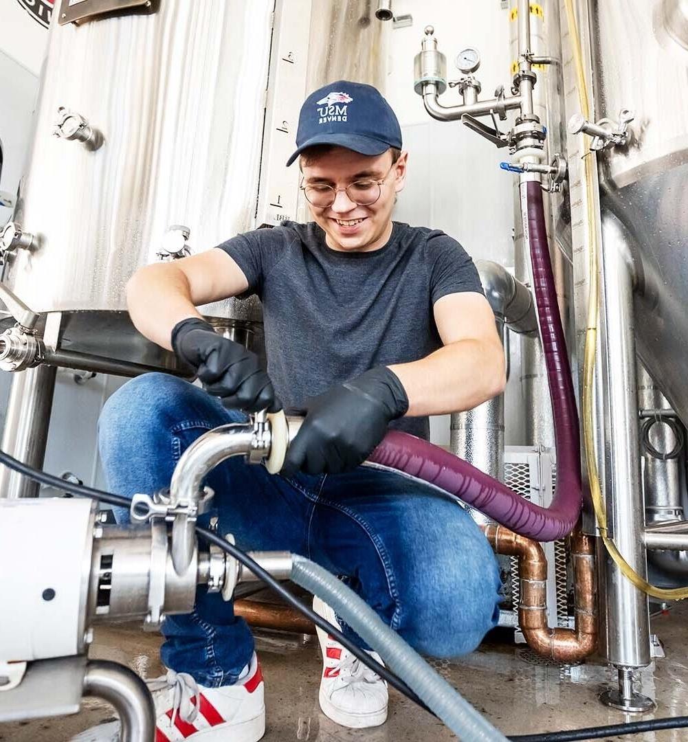 man attaching hoses in brewery