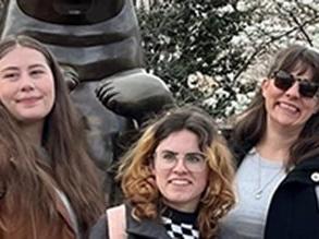 3 students standing in front of a bronze sculpture.